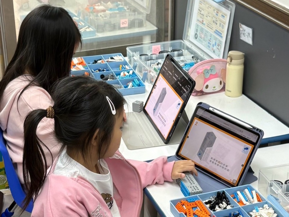 高雄左營教室 STEAM 創意機械積木課,學生看著平板上的組裝步驟動手拼裝零件