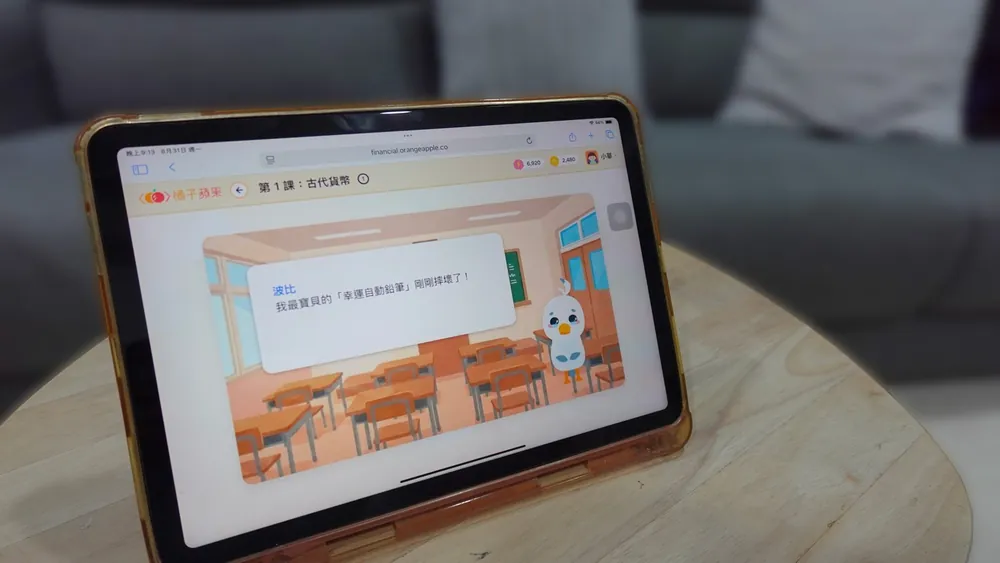 孩子以平板操作財商學習平台第 1 課「古代貨幣」的小故事：角色波比在教室裡說「我最寶貝的『幸運自動鉛筆』剛剛摔壞了！」
